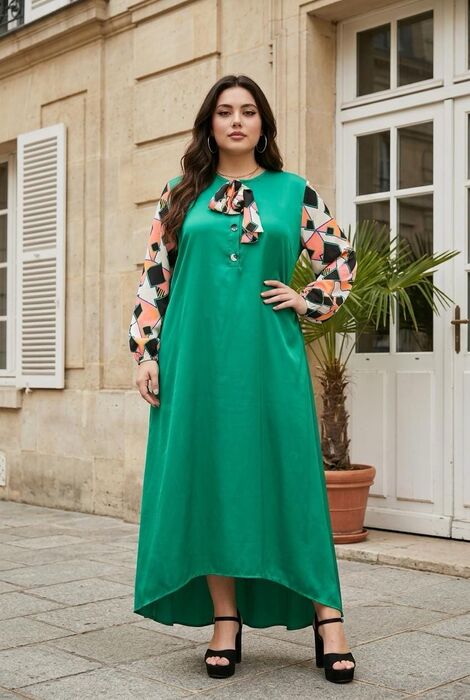 A floor-length emerald green dress featuring long sleeves with a geometric pattern in black, white, and peach. The dress has a round neckline with a decorative neck tie, a button-d