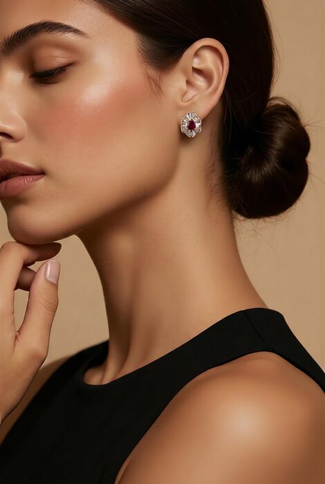 A stud earring featuring a central pear-shaped deep red gemstone surrounded by a halo of clear baguette-cut stones set in a metallic frame. The design creates a floral-like appeara